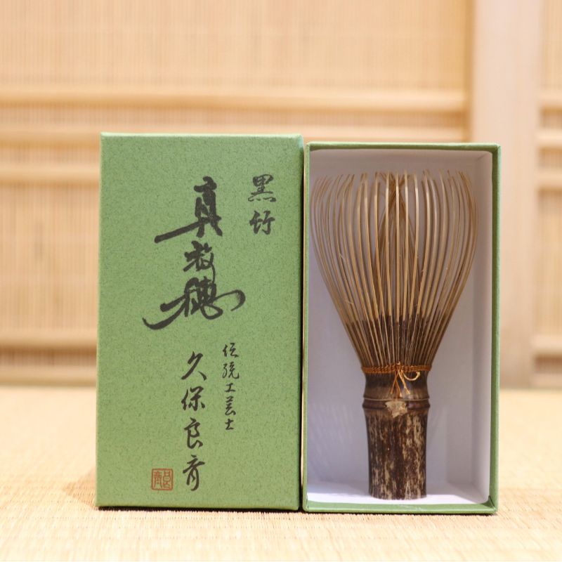 Ryosai Kubo handcrafted Takayama chasen made from Japanese black bamboo with Bronze #19 thread, displayed beside its presentation box