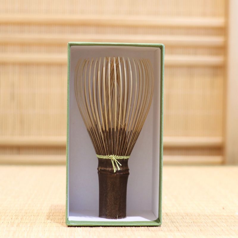 Ryosai Kubo black bamboo Takayama chasen with Lemon #17 thread displayed upright inside its green presentation box