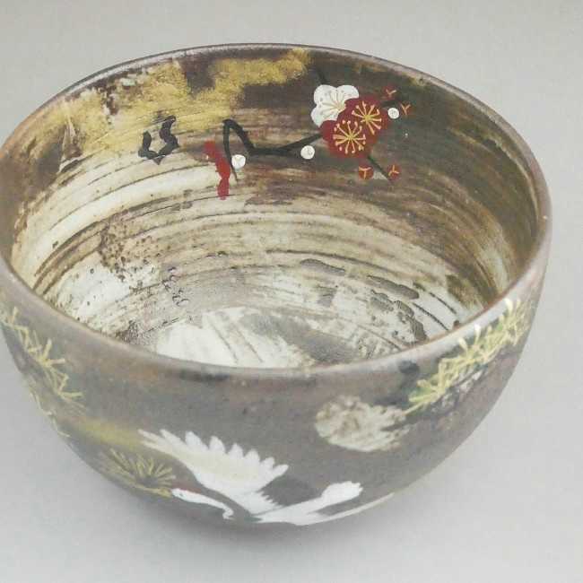 Angled top view showing the decorated interior of the Sakata Yahata matcha bowl, with cranes and plum blossoms continuing across the inner surface.