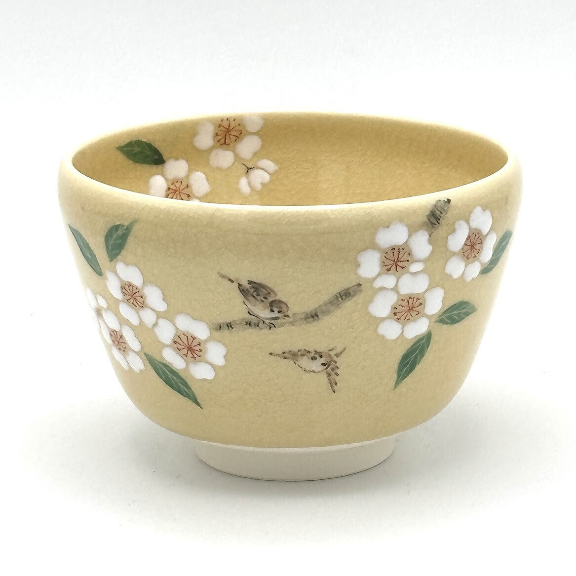 Front view of a hand-painted Kyo Ware matcha bowl decorated with cherry blossoms and two songbirds.