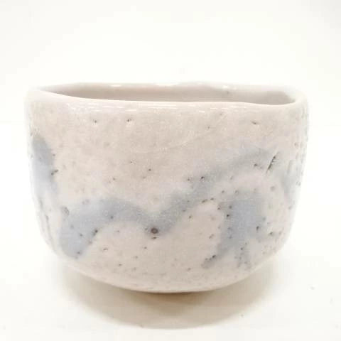 Front view of the Shigezo Sato Benishino chawan showing its milky ivory glaze, softly irregular rim, and misty blue-gray brushwork.