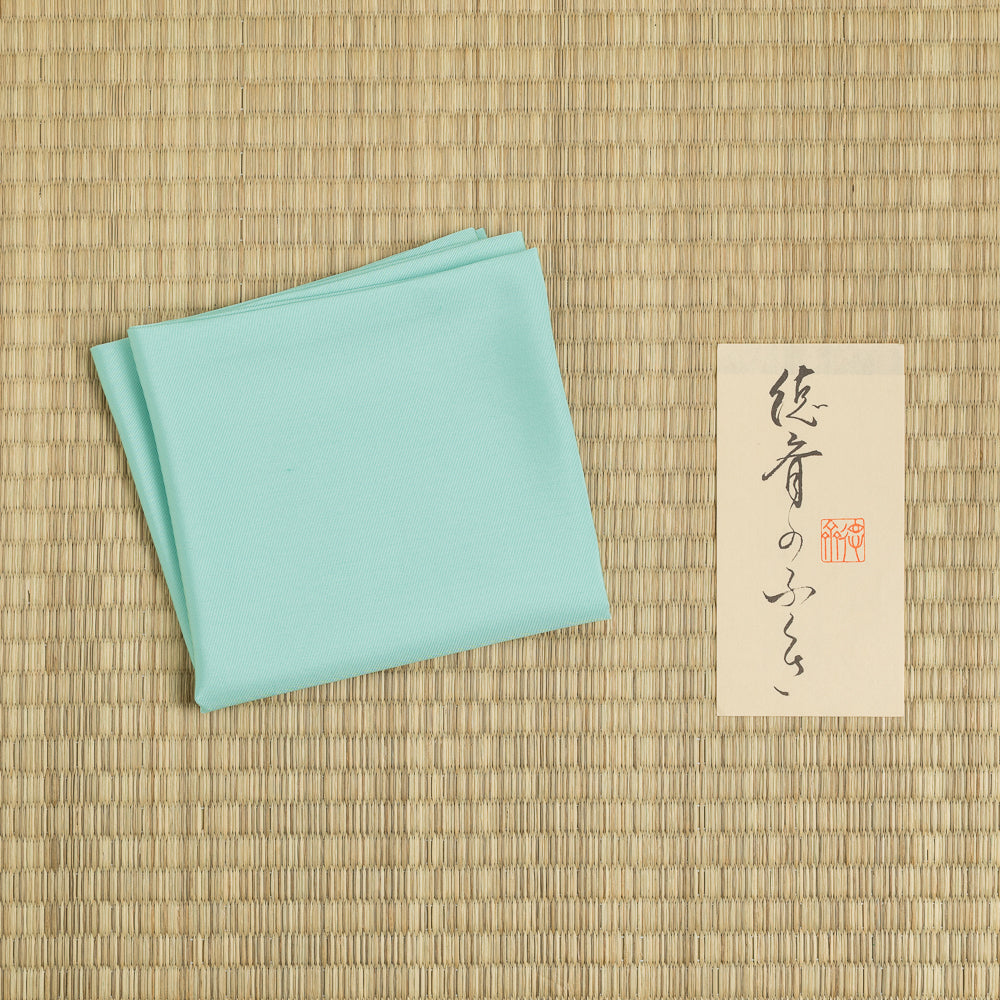 Shinbashi mint green silk fukusa displayed on tatami mat for traditional Japanese tea ceremony practice.