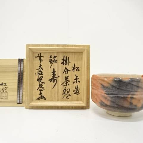 Pre-owned Shoraku Sasaki Kotobuki Red Raku matcha bowl with flowing charcoal glaze displayed beside its wooden hakogaki box inscribed by Etsudo Takahashi