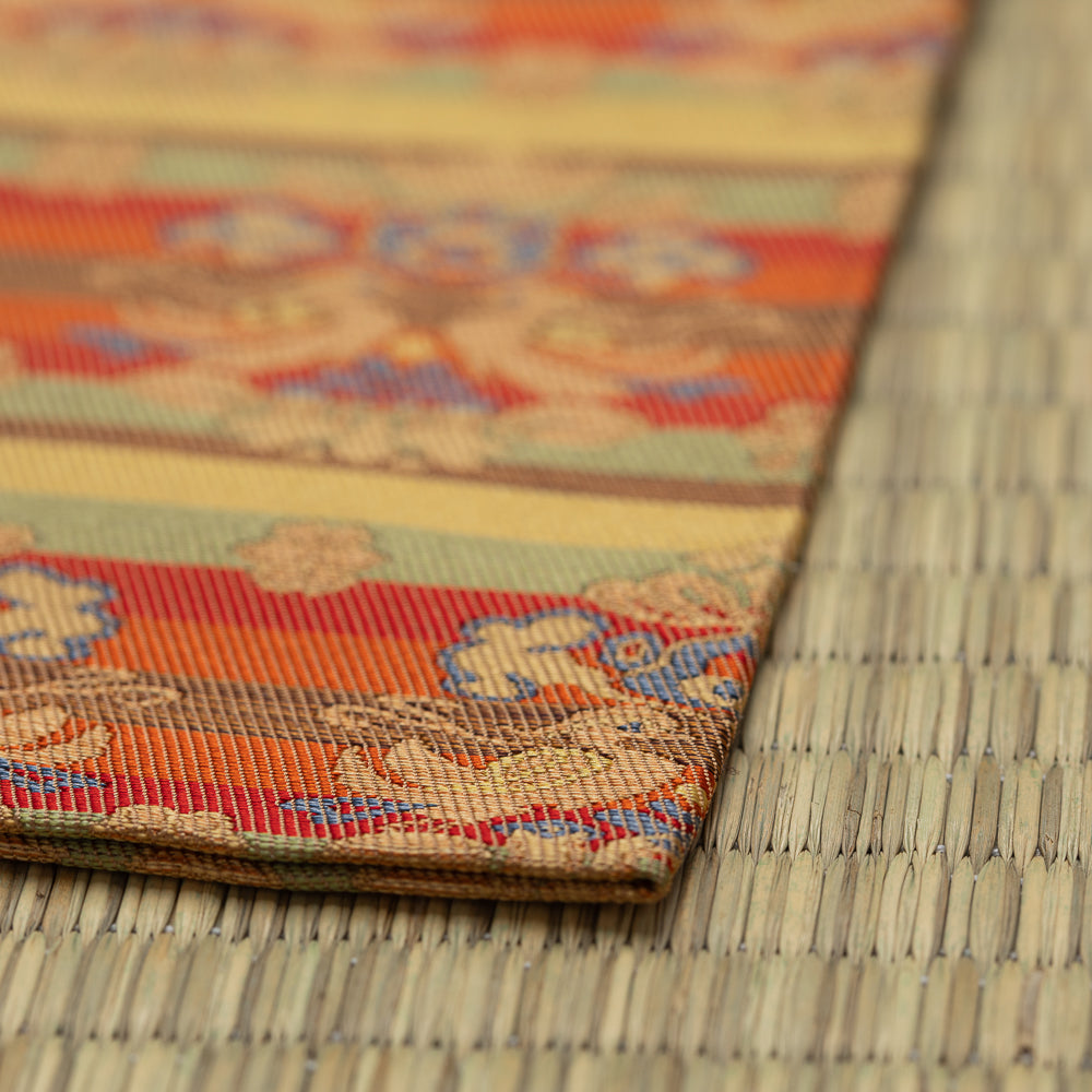 Angled detail of the folded kobukusa showing its woven border, silk texture, and layered floral-and-bird pattern.