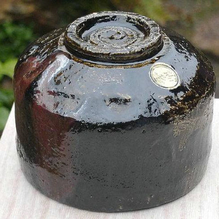 Underside view of the Shuraku Kiln Black Raku matcha bowl showing its circular foot and glossy hand-formed base.