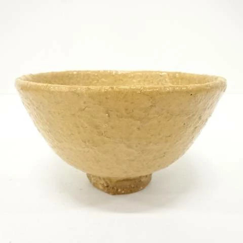 Front view of the Takashi Ajishita Hagi chawan showing its gently flared form, irregular rim, and warm golden-beige speckled glaze.