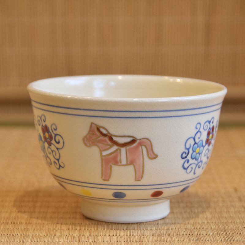 Side view of the Kyo Ware matcha bowl showing a brown zodiac horse between colorful plum blossom and arabesque decorations.