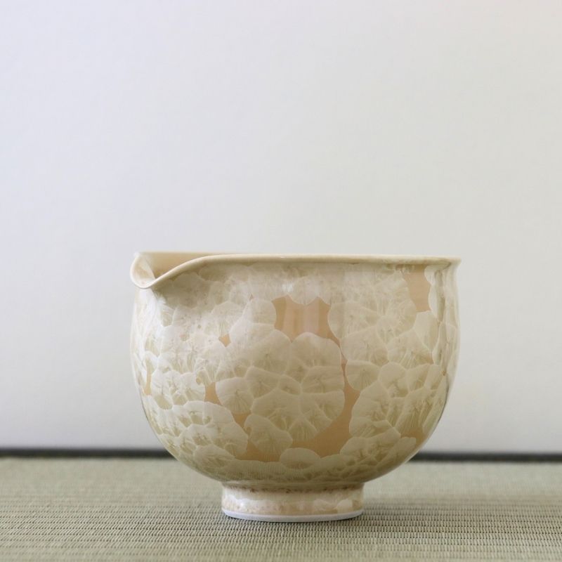 Side view of the Tōan Hana-Kesshō golden flower katakuchi bowl showing its rounded form, pouring spout, and layered cream crystalline glaze