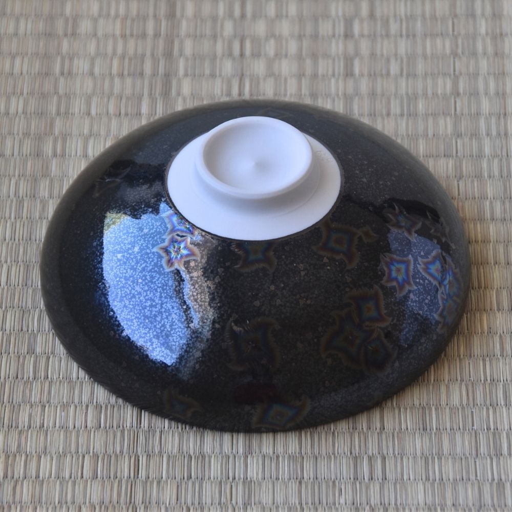 Underside view of the Touan Hoshi-Kessho flat matcha bowl showing its raised white ceramic foot and black crystalline glazed exterior