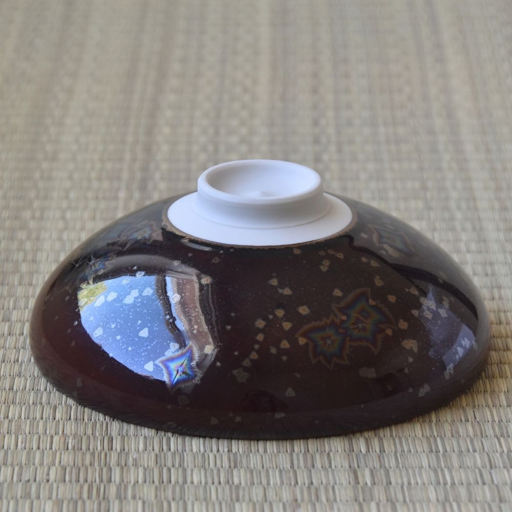 Angled underside view of the Touan Hoshi-Kessho matcha bowl showing its raised white ceramic foot and glossy wine red Star Crystal glaze