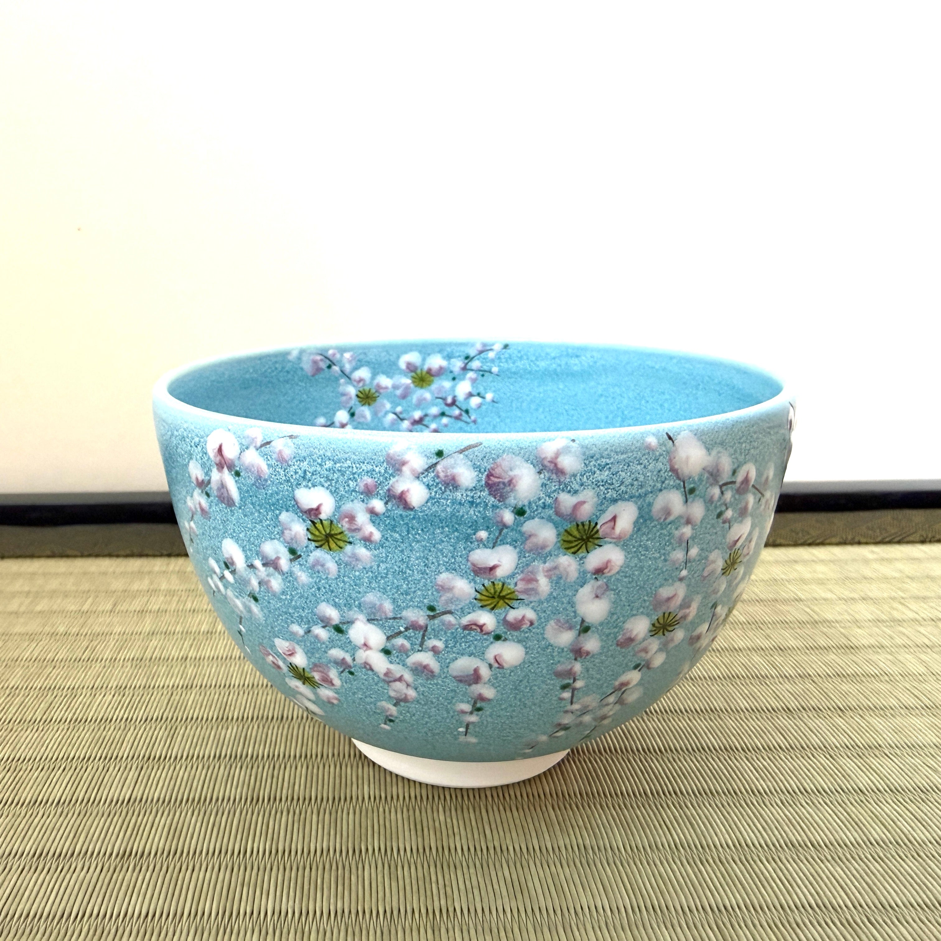 Front angled view of the Kato Eizan chawan showing weeping sakura branches flowing across the luminous turquoise exterior.