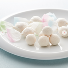White spherical candies on a white plate with a light blue background