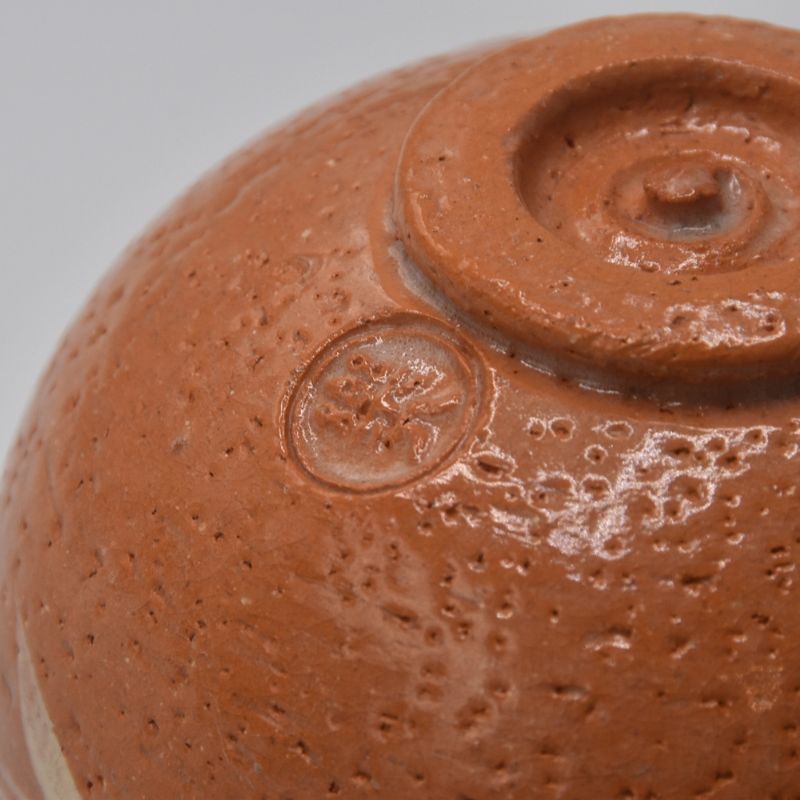 Close-up of the circular Yoshimura Raku-nyu maker's mark impressed near the foot of the matcha bowl.