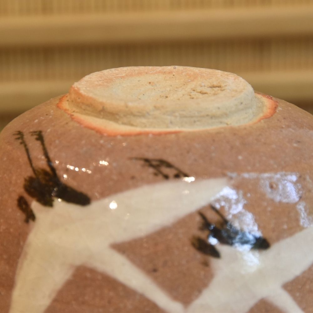 Close-up of the underside of the Dancing Cranes matcha bowl showing its exposed foot, maker's mark, and painted crane detail.