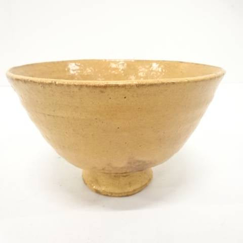 Front studio view of the Zuiho Ono Hagi chawan showing its gently flared Ido-style form, raised foot, and warm honey-amber glaze.