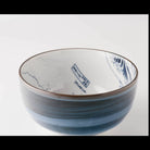 A ceramic bowl with a blue and white hand-painted wave design and brushstroke texture, photographed on a clean white background.