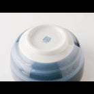 Close-up of the bottom of a glossy ceramic bowl or vase with a white interior and a blue-gray marbled exterior, photographed on a clean white background.