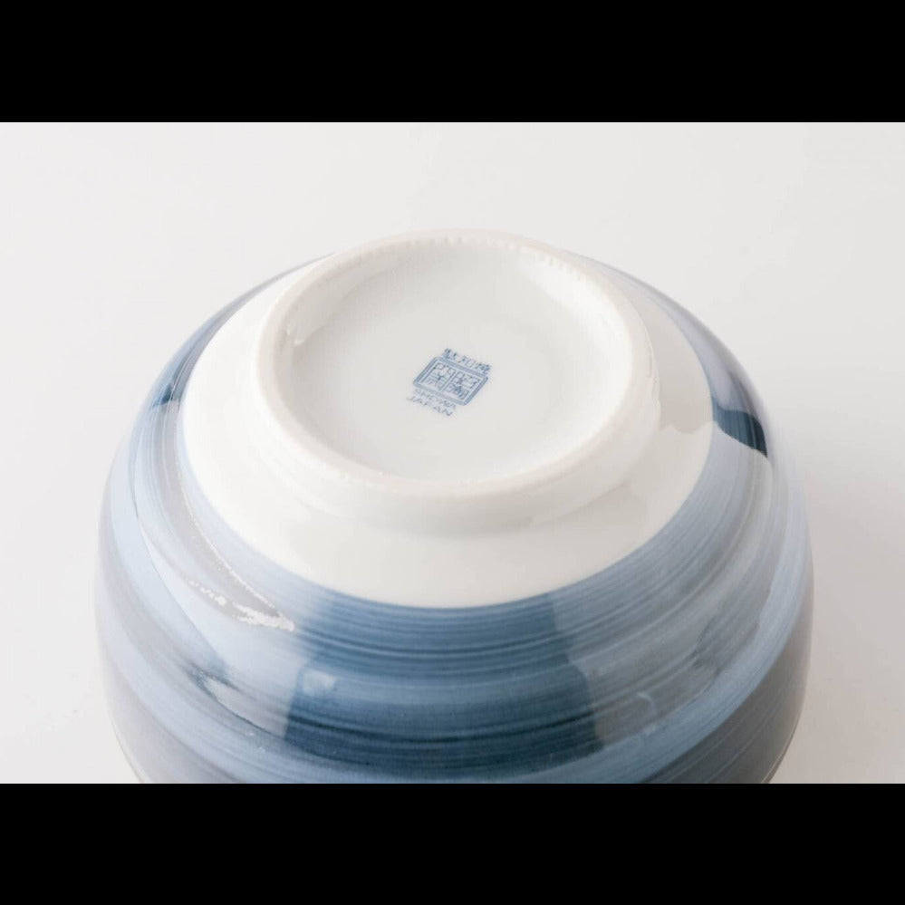 Close-up of the bottom of a glossy ceramic bowl or vase with a white interior and a blue-gray marbled exterior, photographed on a clean white background.