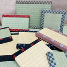Collection of woven mats with various patterns and colors on a wooden floor.