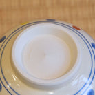 Close-up of a ceramic dish with a white center and blue rim on a wooden surface
