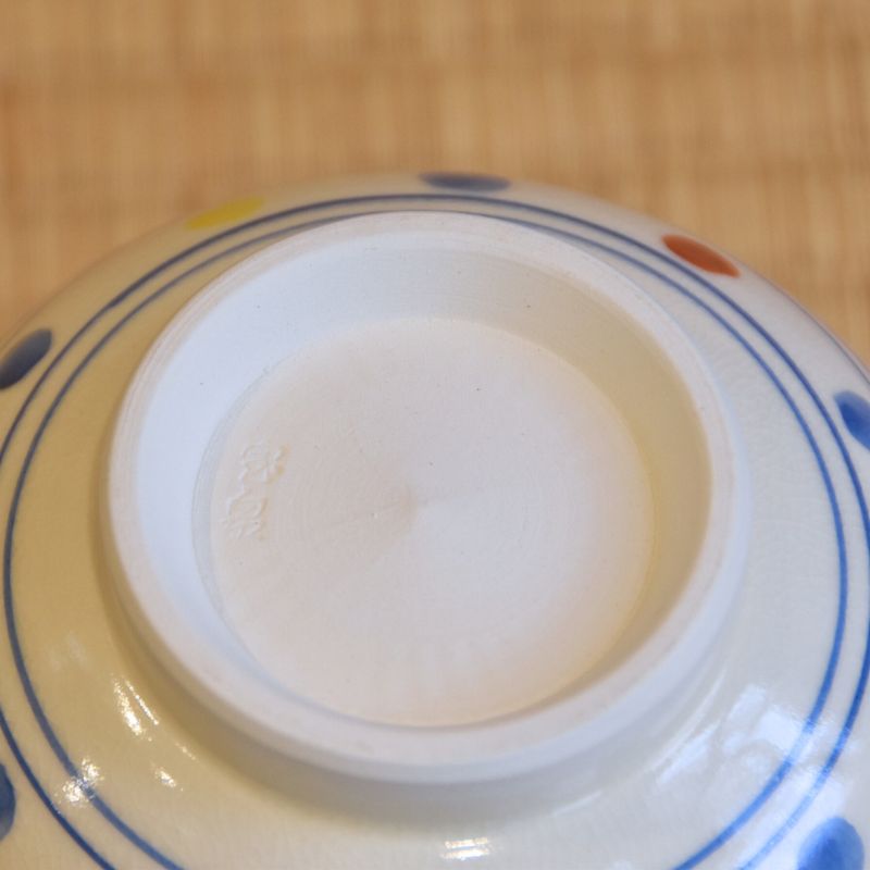 Close-up of a ceramic dish with a white center and blue rim on a wooden surface