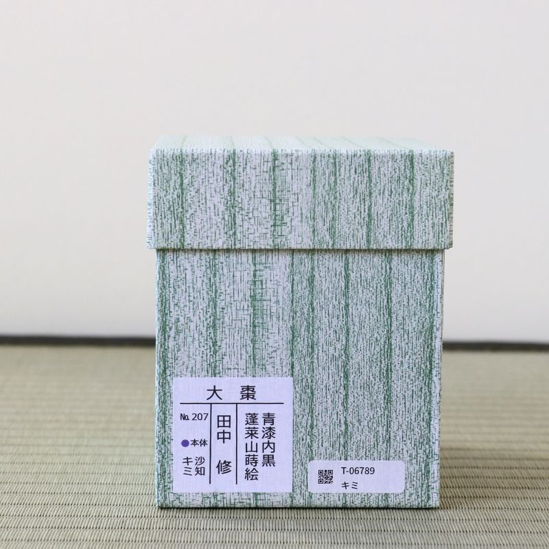 A square light green and white textured box with Japanese characters printed on a white label, placed on a woven mat against a plain light background.