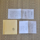 Two pieces of paper with text and a yellow envelope on a woven mat background