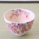 Small ceramic cup with floral pattern on a light wooden surface