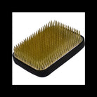 A black rectangular hair tool with dense metallic gold spikes, shown on a plain white background.