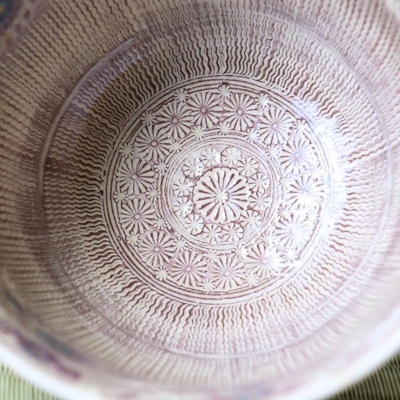 Close-up of the inside of a ceramic bowl with a hand-painted lavender and white floral pattern in concentric circles.