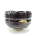 Black ceramic bowl with gold interior on a white background