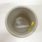 Small ceramic cup with a yellow object inside on a white background