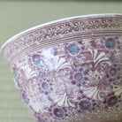 A close-up of a ceramic bowl featuring a textured, rustic brown and white floral pattern with purple and blue flower accents.