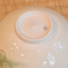 Close-up of a ceramic bowl's base with a brand logo on a wooden surface