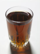 Glass of amber liquid on a white background