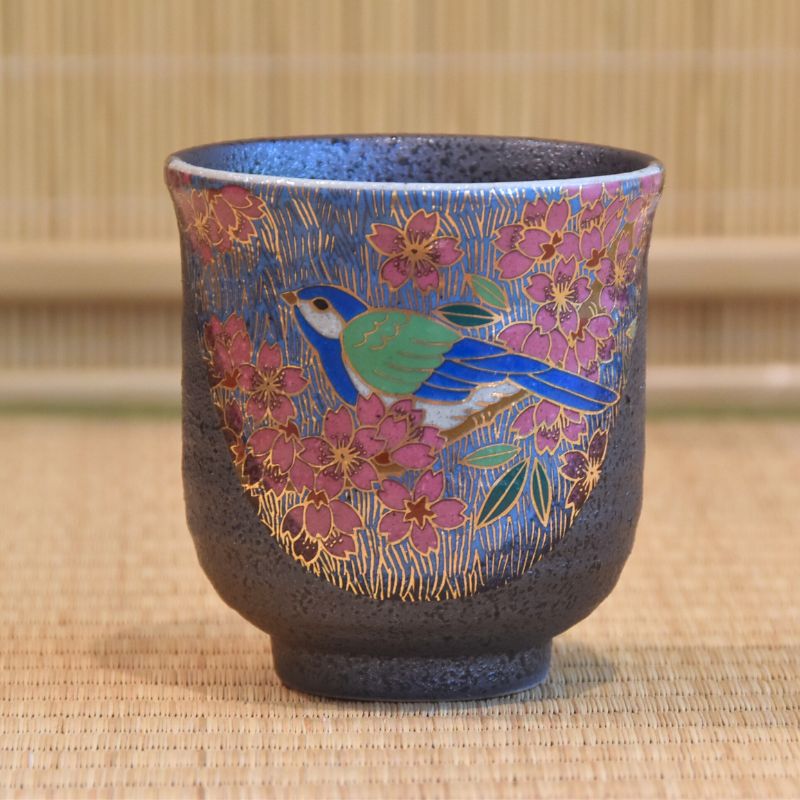 Ceramic cup with floral and bird design on a woven mat background