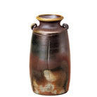 A rustic ceramic vase with a dark brown and black glaze, featuring a warm orange-brown mottled pattern near the base and a light beige rim, set against a plain light gray background.