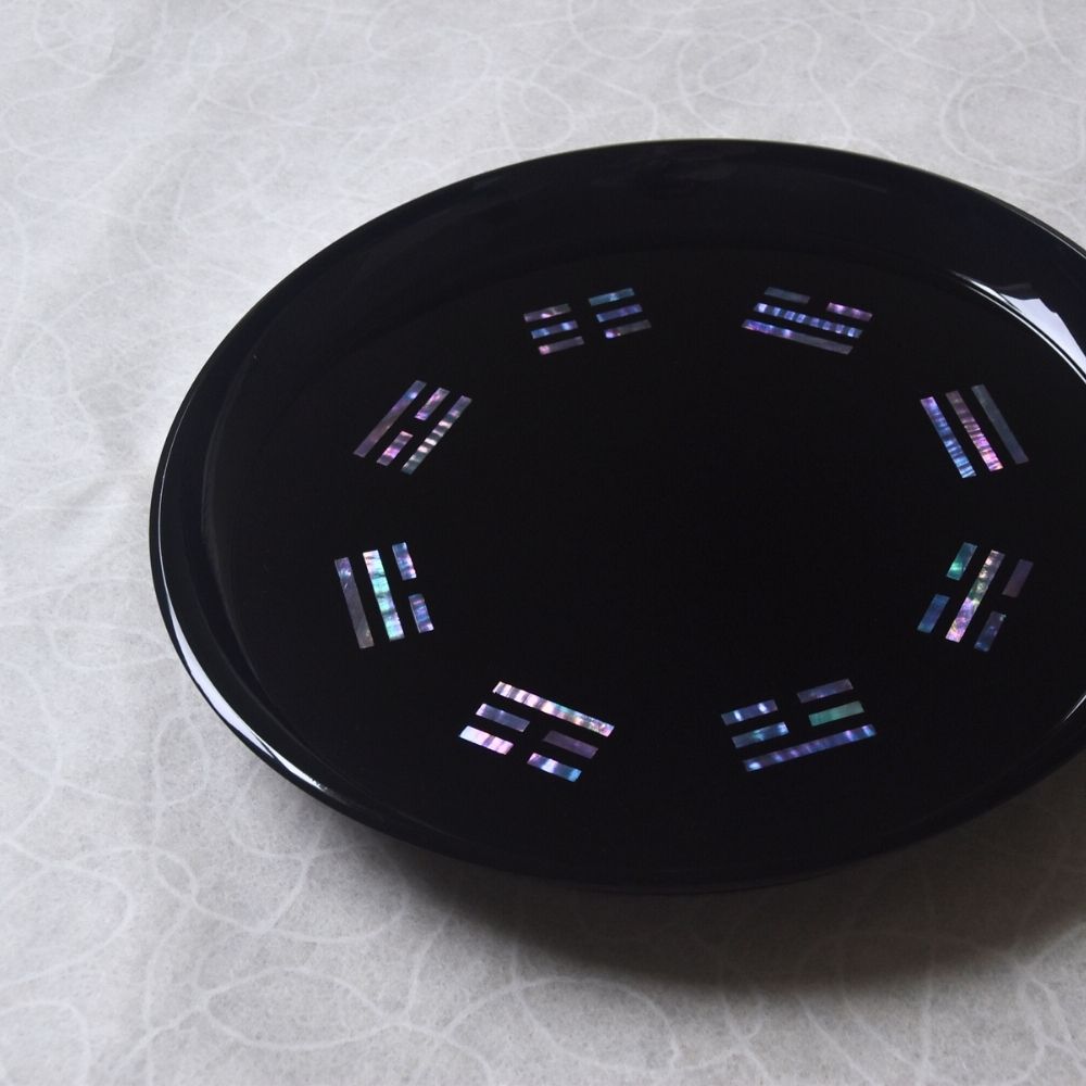 Black circular object with colorful patterns on a textured white background