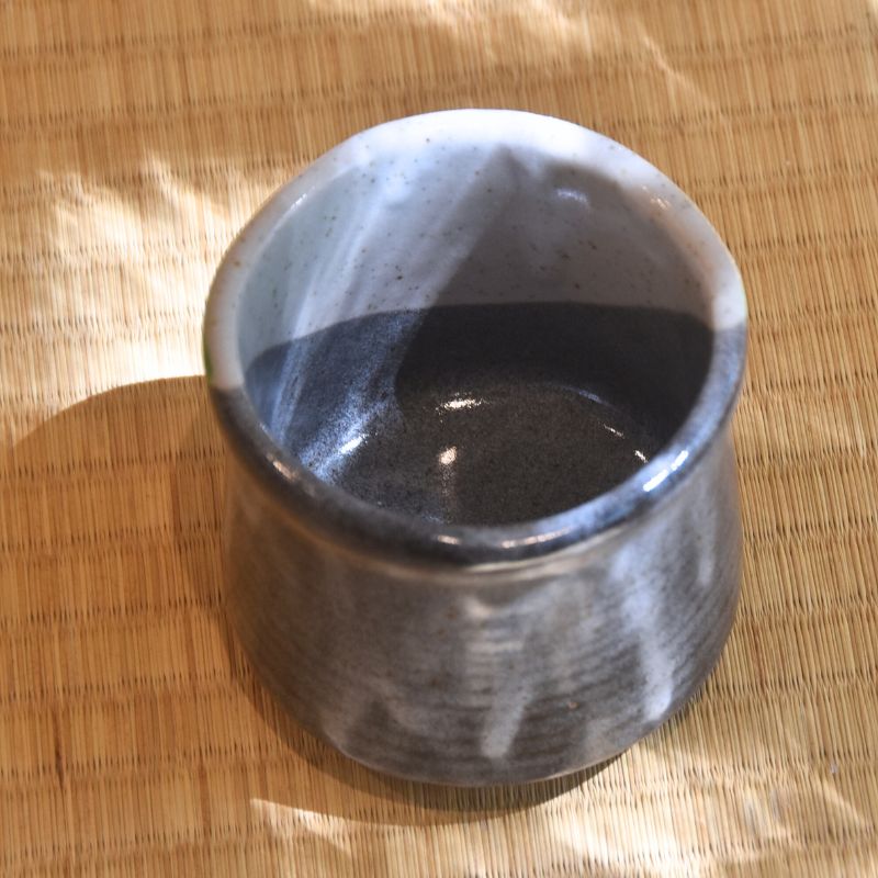 Black ceramic cup on a woven mat