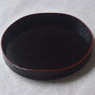 Black lacquer tray with red interior on a light gray background