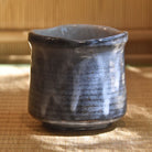 Blue ceramic cup on a woven mat with a blurred background