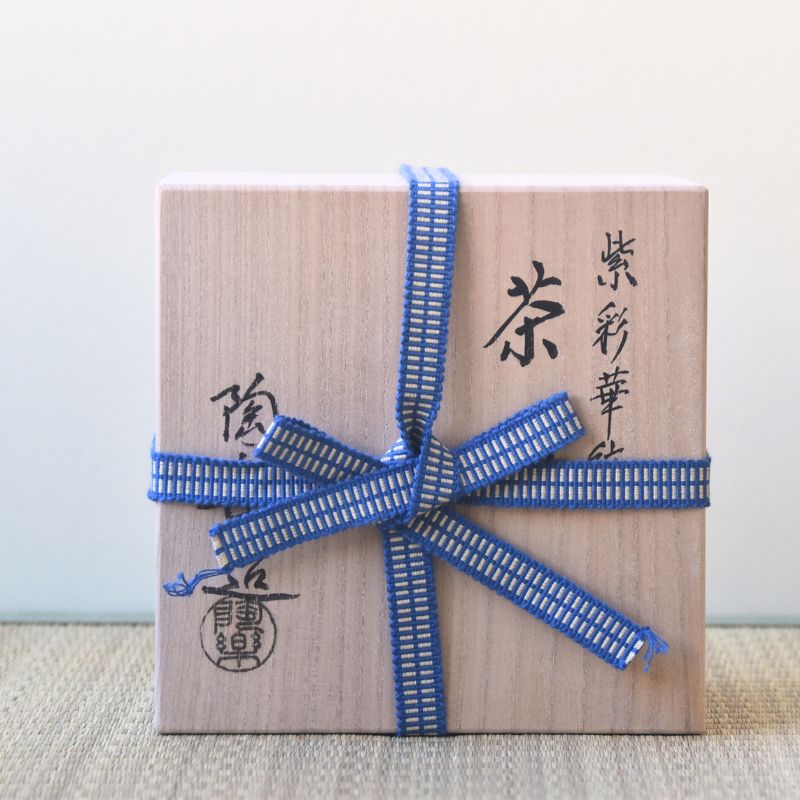 Wooden box with blue ribbon and Japanese text on a light background