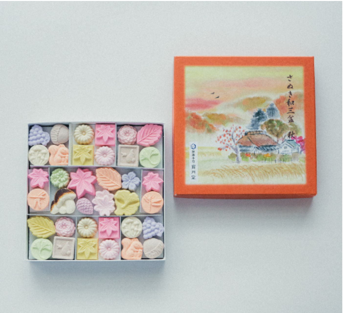 Box of assorted pastries with a decorative lid featuring an illustration on a white background