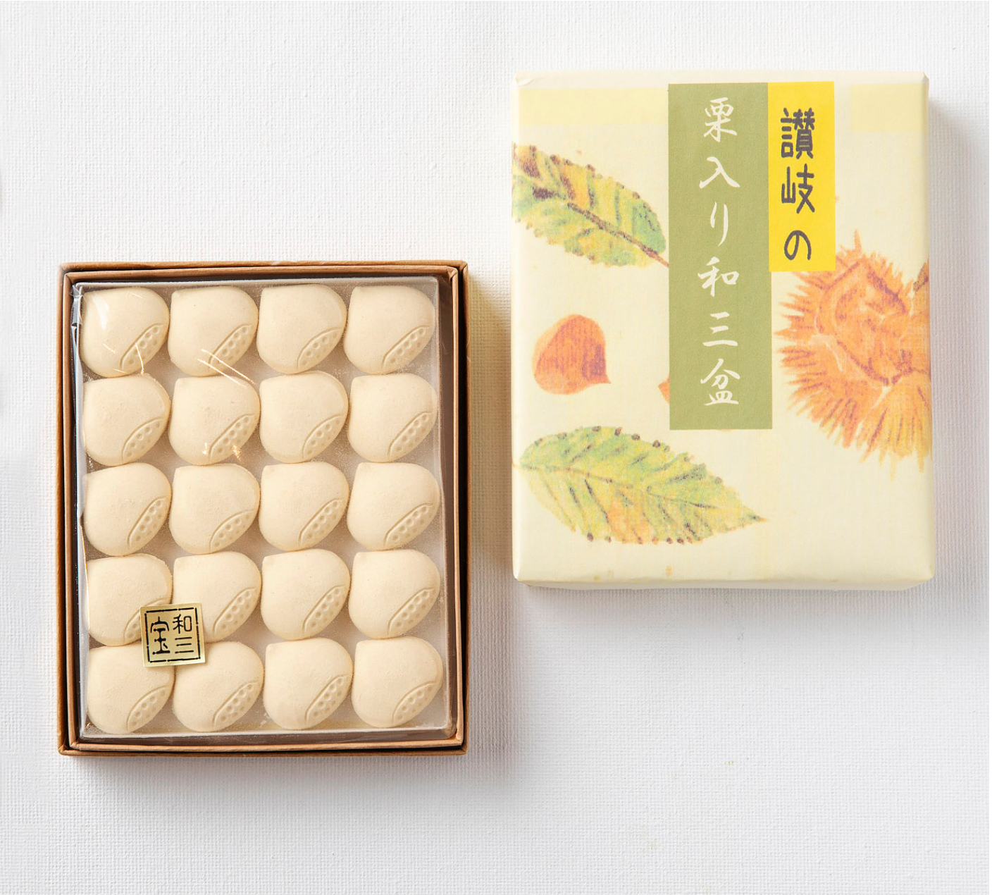 Box of white cookies next to a decorative box with floral design on a light gray background