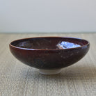 Brown ceramic bowl on a textured surface with a neutral background