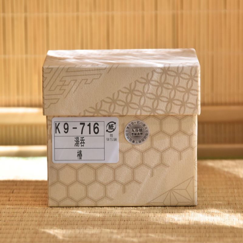 Brown paper box with hexagonal pattern and labels on a bamboo background