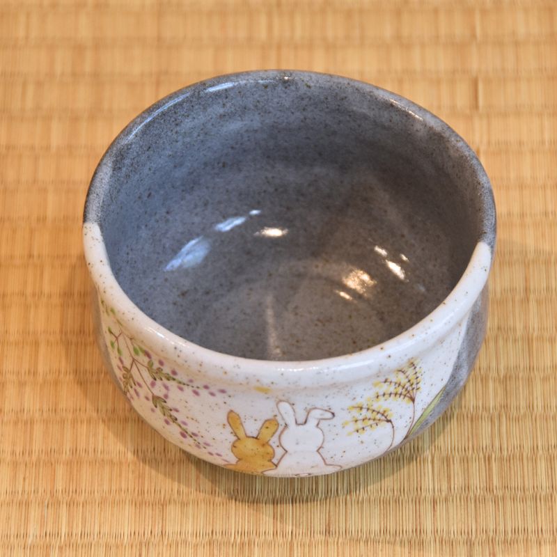 Ceramic bowl with rabbit design on a bamboo mat