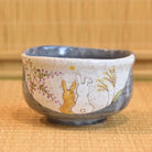 Ceramic bowl with rabbit design on a bamboo mat