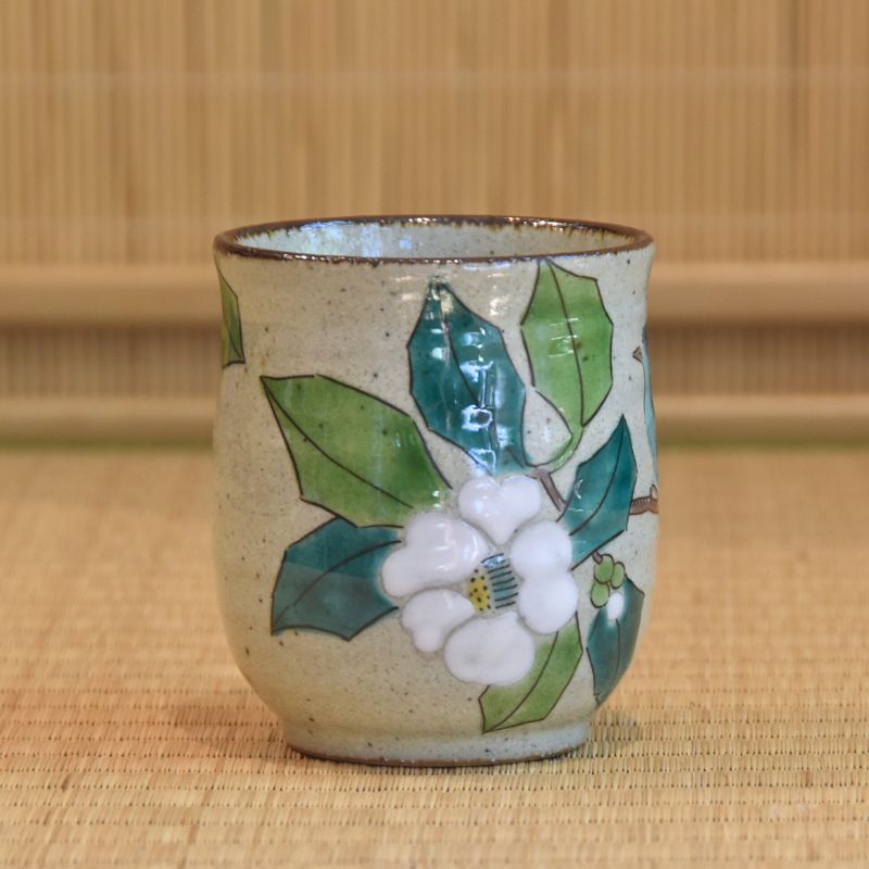 Ceramic cup with floral design on a woven mat