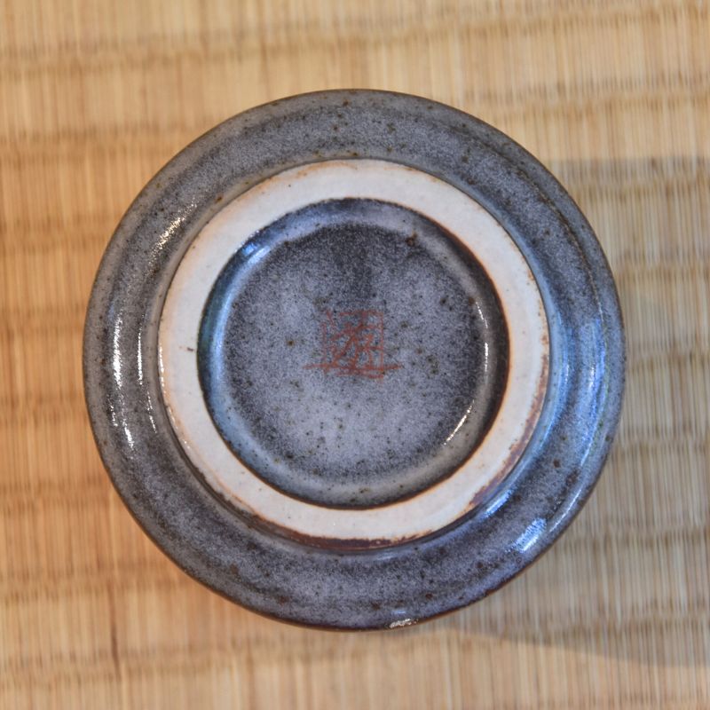 Ceramic dish with a signature on a wooden surface